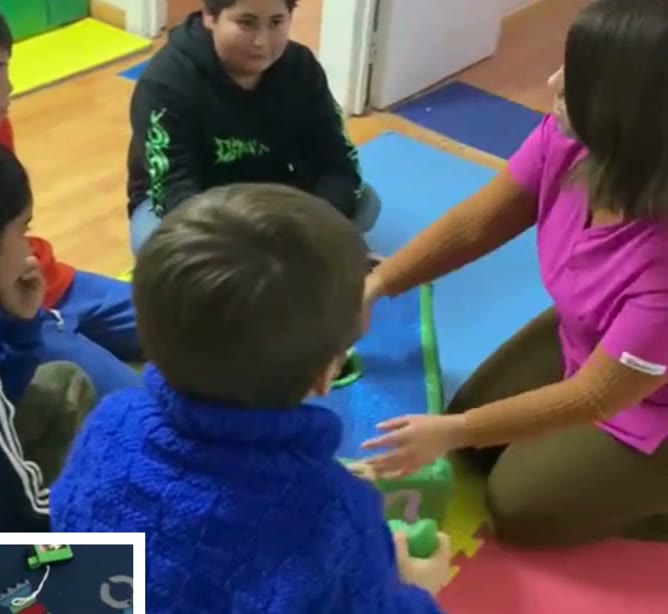 Terapeuta trabajando con un grupo de niños sobre el piso de goma